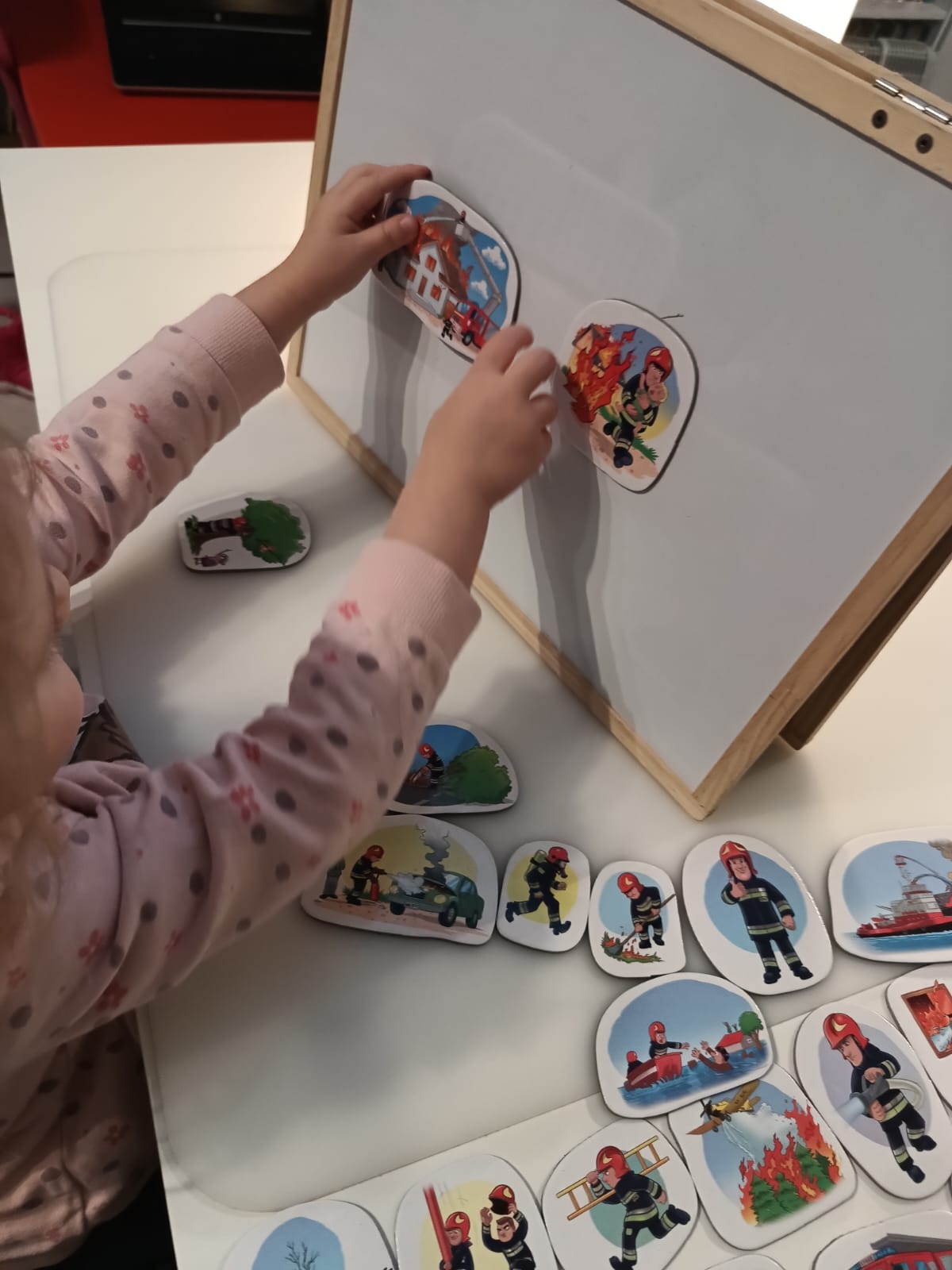 Dziewczynka przy tablicy z magnetycznymi kartami strażaka